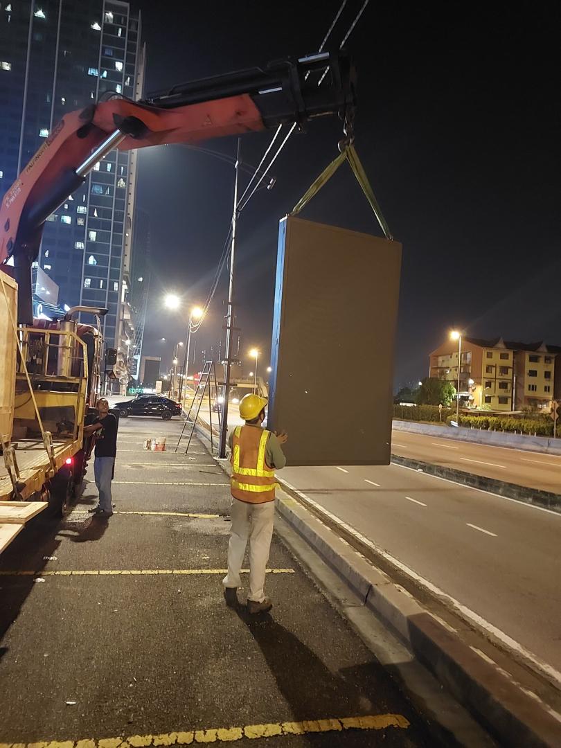 LED billboard cabinet being lifted during a night roadside installation